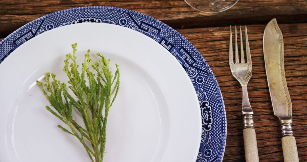 A sprig of greenery is placed on an ornate plate, flanked by vintage silverware, with copy space - Free Images, Stock Photos and Pictures on Pikwizard.com