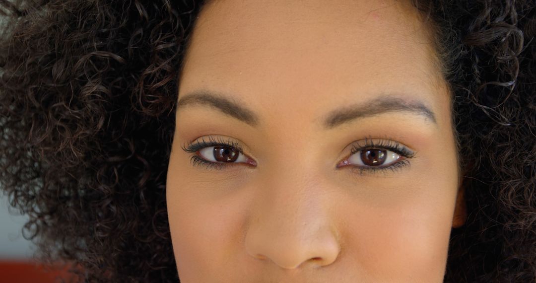 Close-up of Woman with Curly Hair and Brown Eyes Looking into Camera - Free Images, Stock Photos and Pictures on Pikwizard.com