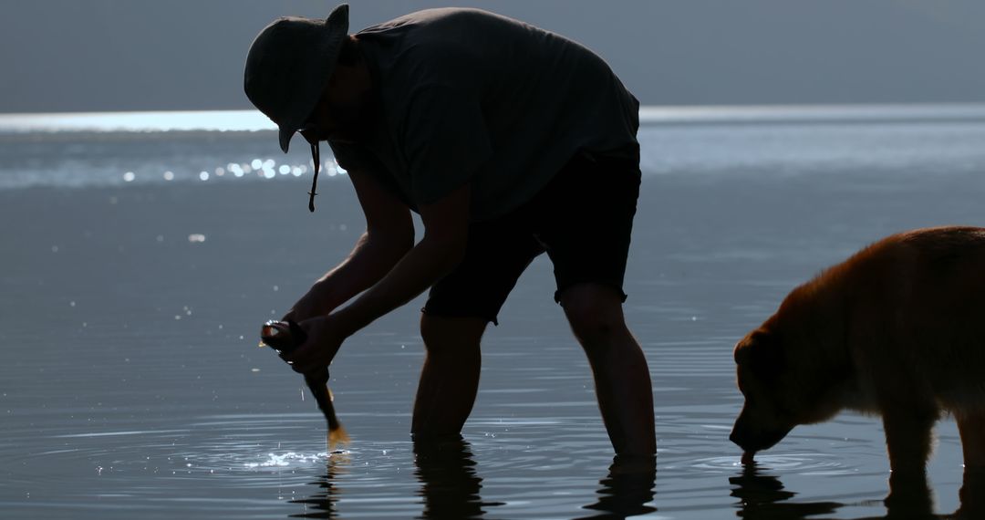 Man Holding Fish with Dog in Lake During Sunset - Free Images, Stock Photos and Pictures on Pikwizard.com