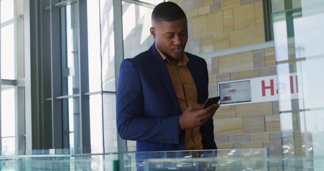 Businessman Checking Smartphone in Modern Office Lobby - Free Images, Stock Photos and Pictures on Pikwizard.com