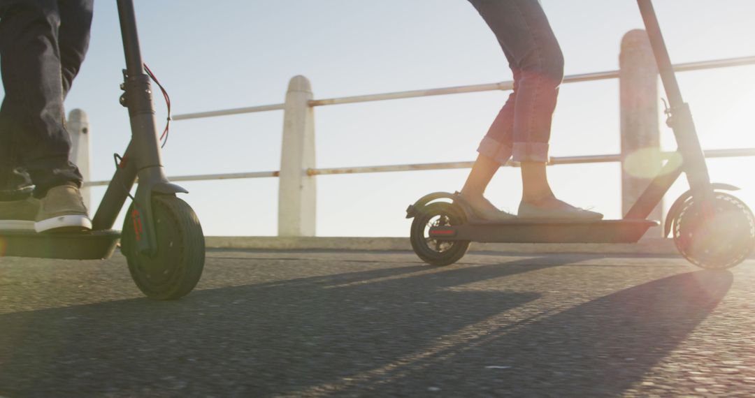 Low-Angle View of Two People Riding Electric Scooters on Sunny Day - Free Images, Stock Photos and Pictures on Pikwizard.com