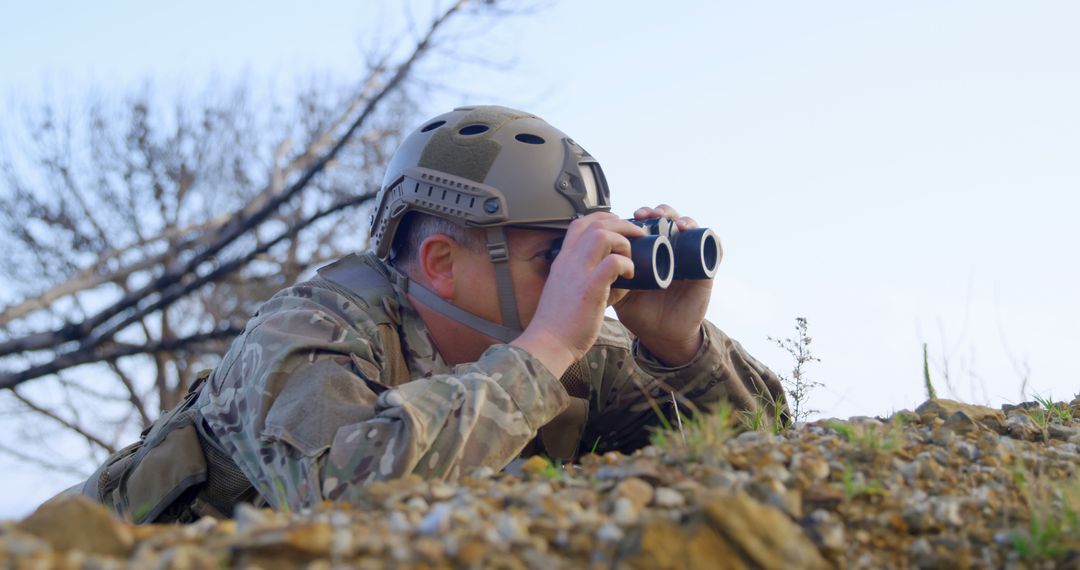 Soldier In Full Gear Observing With Binoculars In Camouflaged Position - Free Images, Stock Photos and Pictures on Pikwizard.com