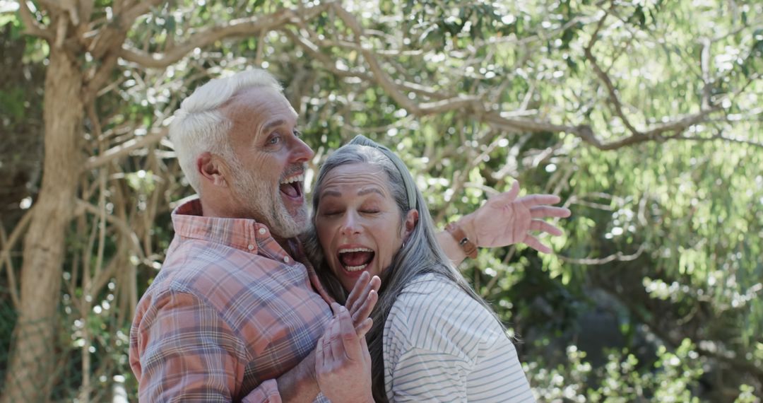 Cheerful Senior Couple Laughing Outdoors in Sunny Forest - Free Images, Stock Photos and Pictures on Pikwizard.com