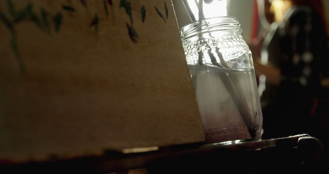 Jar of Paintbrushes Positioned Next to Canvas in Warm Light - Free Images, Stock Photos and Pictures on Pikwizard.com