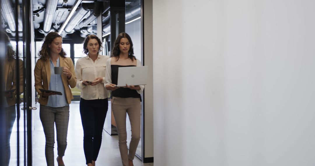 Diverse Female Team Collaborating in Modern Office Corridor