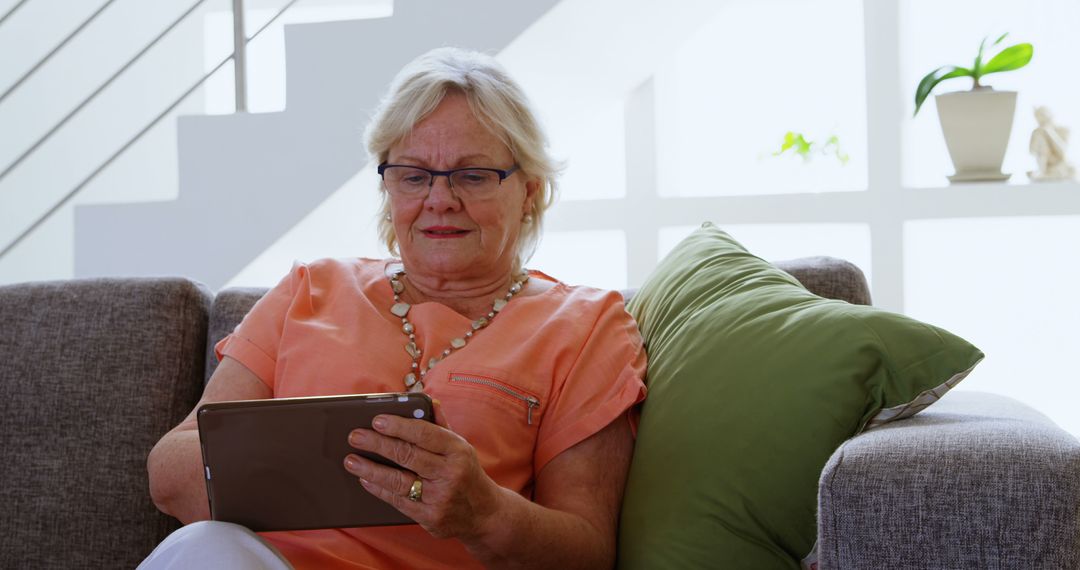 Elderly Woman Using Tablet on Sofa at Home - Free Images, Stock Photos and Pictures on Pikwizard.com