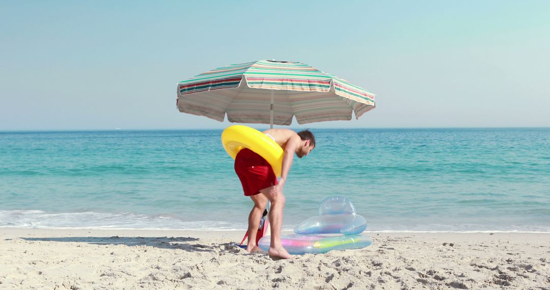 Man Enjoying Beach with Inflatable Toy Under Parasol - Free Images, Stock Photos and Pictures on Pikwizard.com