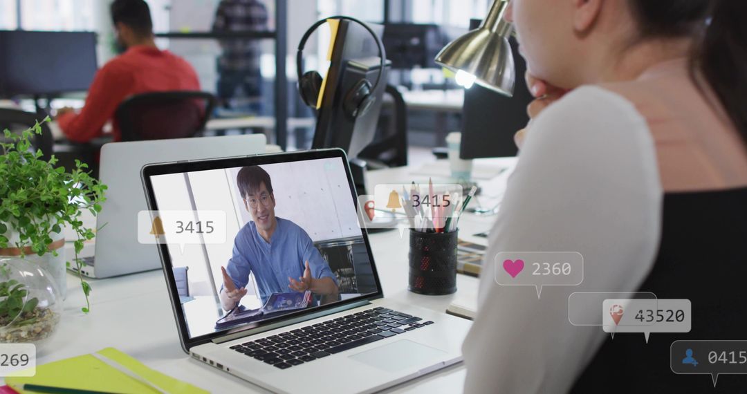Korean presenter gesturing on laptop during virtual meeting with social engagement icons