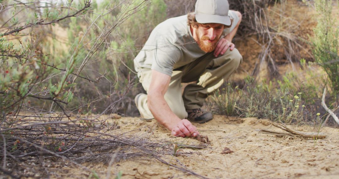 Caucasian male survivalist squatting down and examining animal dropping in wilderness - Free Images, Stock Photos and Pictures on Pikwizard.com