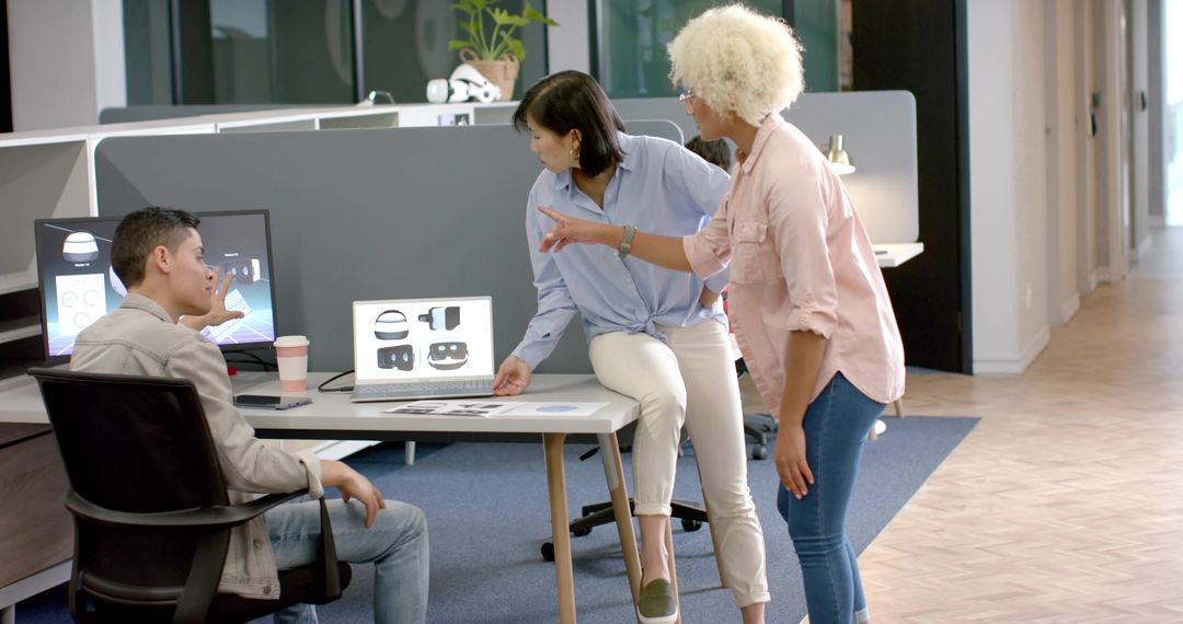 Collaborating on VR headset design in modern open-plan office with laptop and sketches