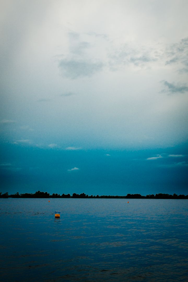 Tranquil Blue Lake with Buoy Under Cloudy Sky - Free Images, Stock Photos and Pictures on Pikwizard.com