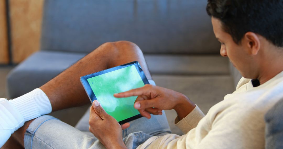 Man Relaxing on Couch Pointing at Tablet Screen - Free Images, Stock Photos and Pictures on Pikwizard.com