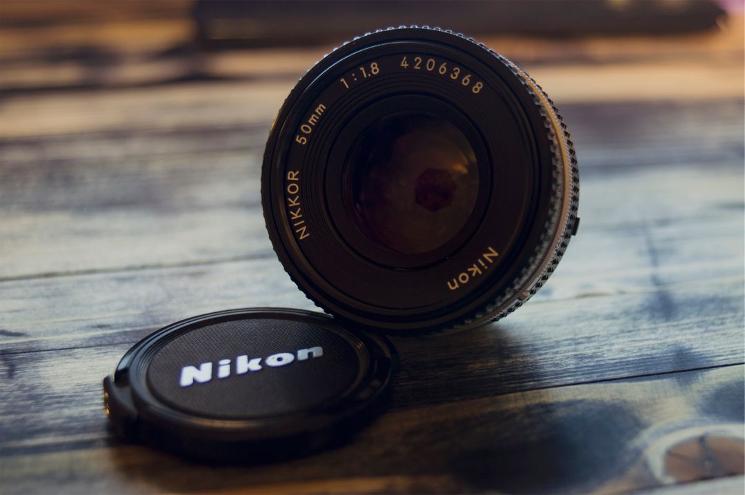 Close-Up of Nikon 50mm Lens with Cap on Wooden Surface - Free Images, Stock Photos and Pictures on Pikwizard.com