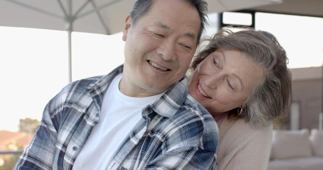 Senior Couple Embracing on Patio in Sunny Setting