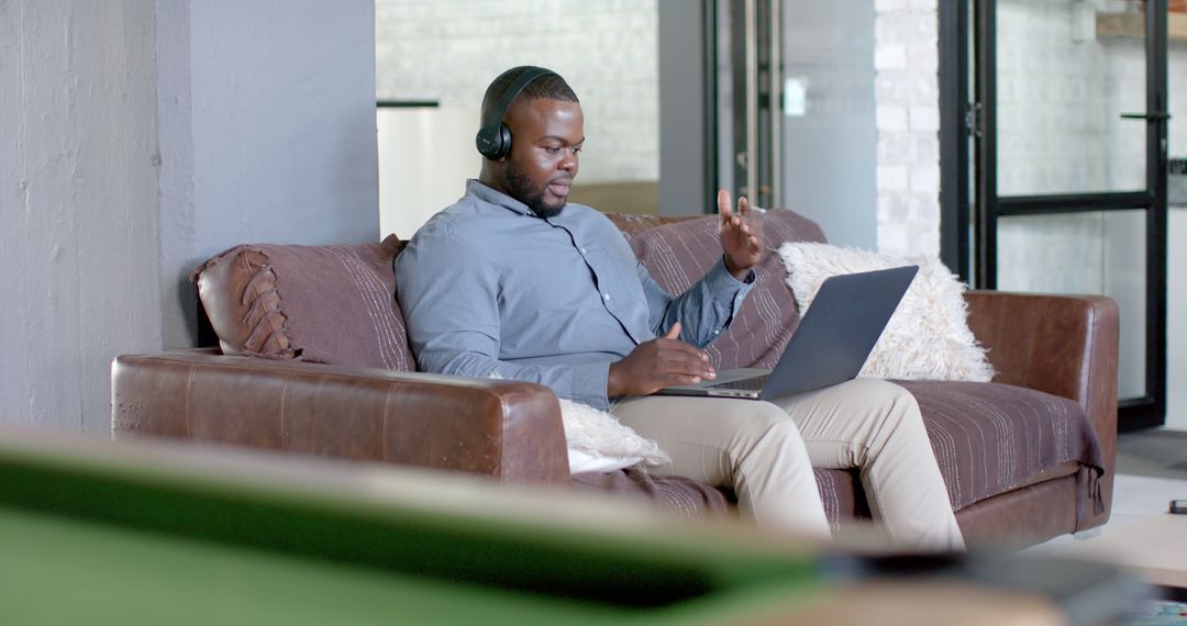 Man Wearing Headphones Working on Laptop from Couch - Free Images, Stock Photos and Pictures on Pikwizard.com