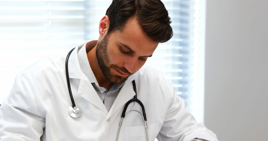 Focused Doctor Writing Patient Notes in Modern Clinic - Free Images, Stock Photos and Pictures on Pikwizard.com