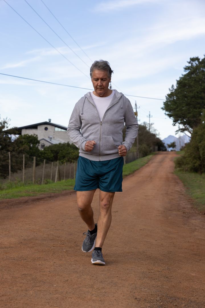Middle-aged Man Jogging on Scenic Rural Pathway in Activewear