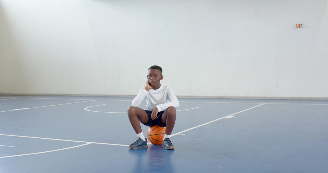 Determined Boy with Basketball Reflecting on School Court