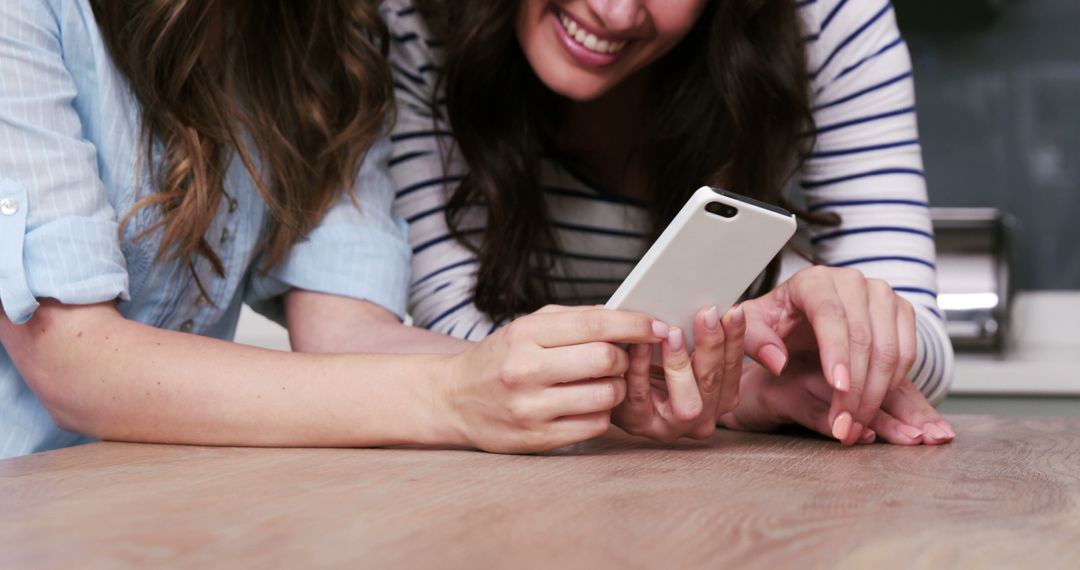 Two Friends Smiling and Using Smartphone Together - Free Images, Stock Photos and Pictures on Pikwizard.com