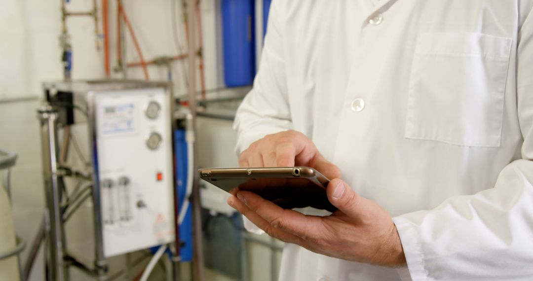 Professional in a lab coat using a smartphone in an industrial setting - Free Images, Stock Photos and Pictures on Pikwizard.com