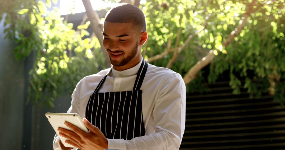 Smiling Chef Using Tablet in Outdoor Setting - Free Images, Stock Photos and Pictures on Pikwizard.com