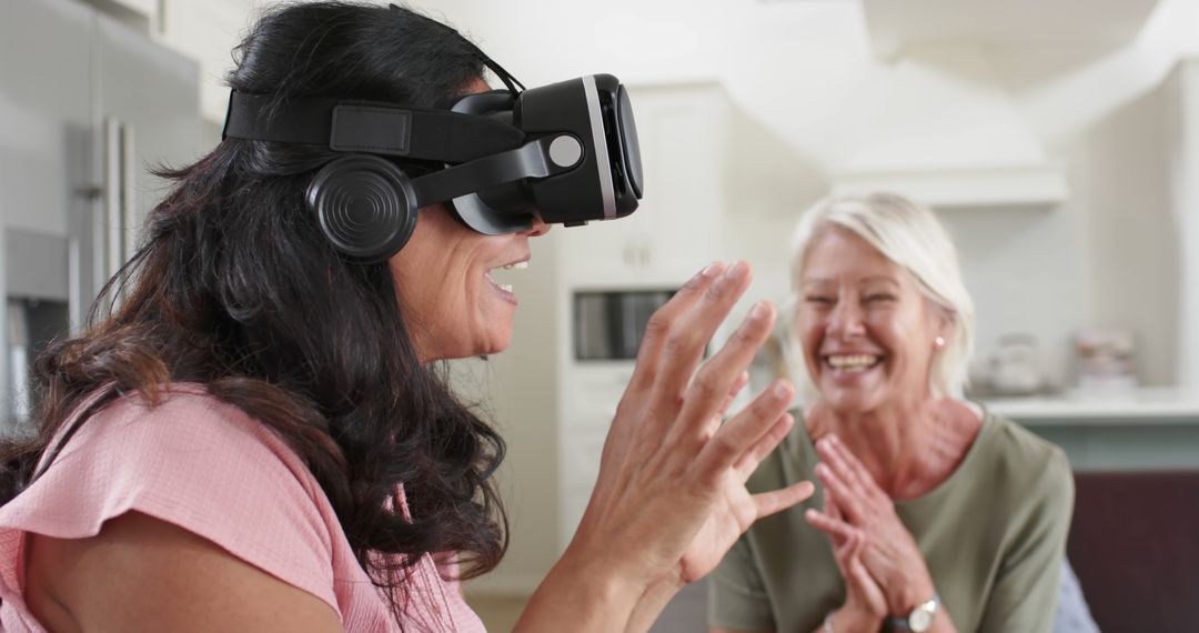 Laughing Woman Experiencing Virtual Reality with Friend in Modern Kitchen - Free Images, Stock Photos and Pictures on Pikwizard.com