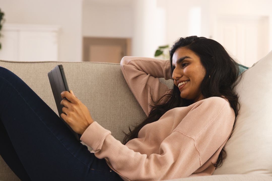 Woman Relaxing on Couch Using Tablet and Smiling