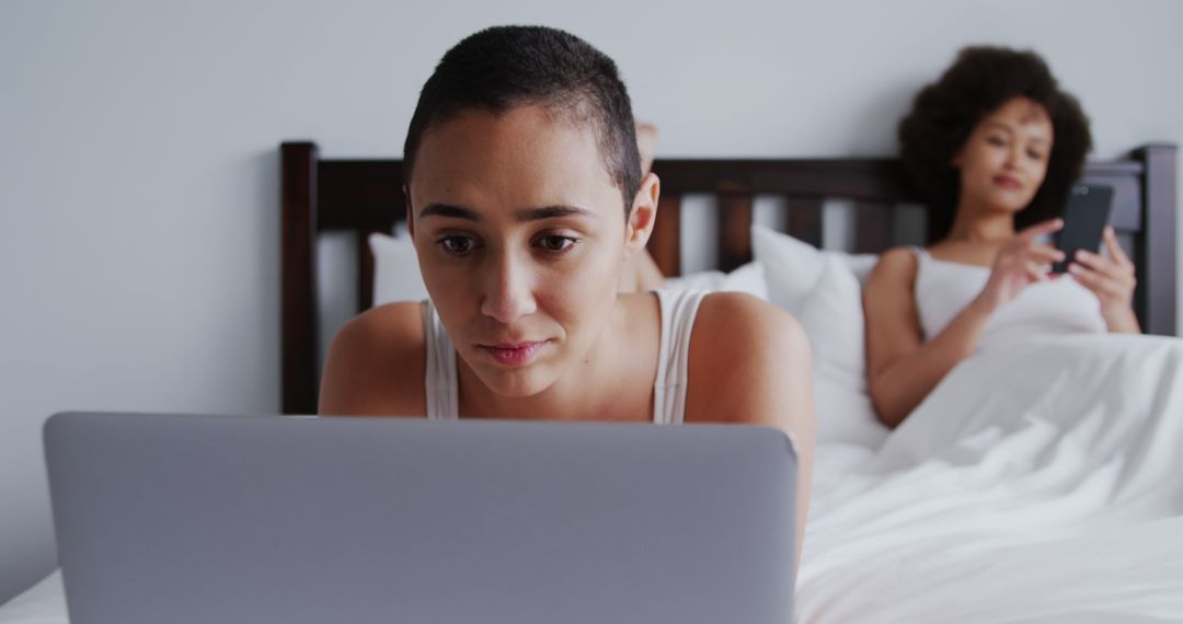 Young Women Relaxing in Bed with Laptop and Smartphone - Free Images, Stock Photos and Pictures on Pikwizard.com