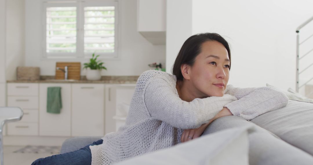 Thoughtful Woman Relaxing on Sofa in Modern Home