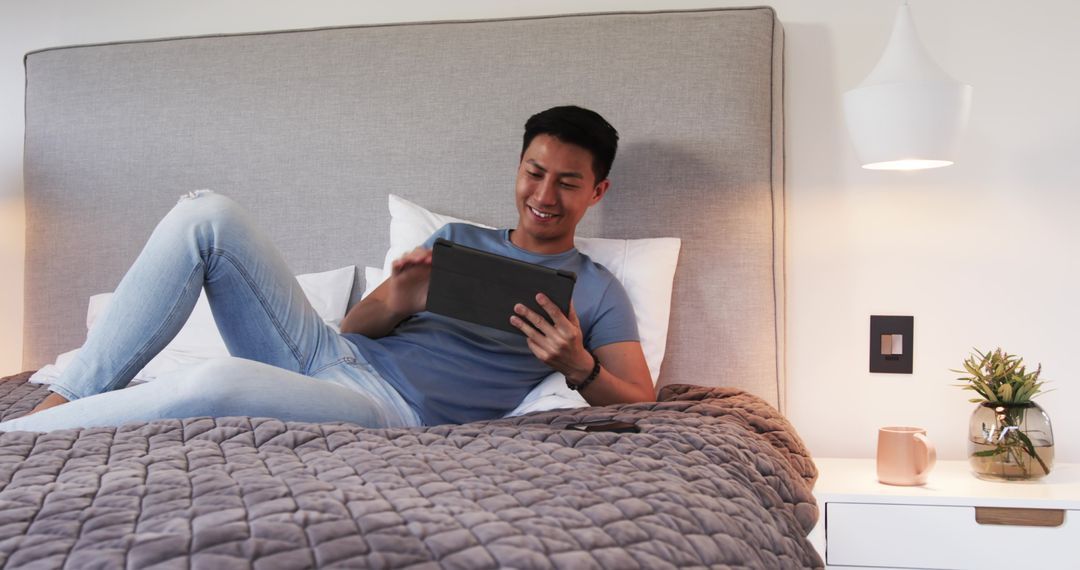 Man Relaxing on Bed Using Tablet in Cozy Bedroom