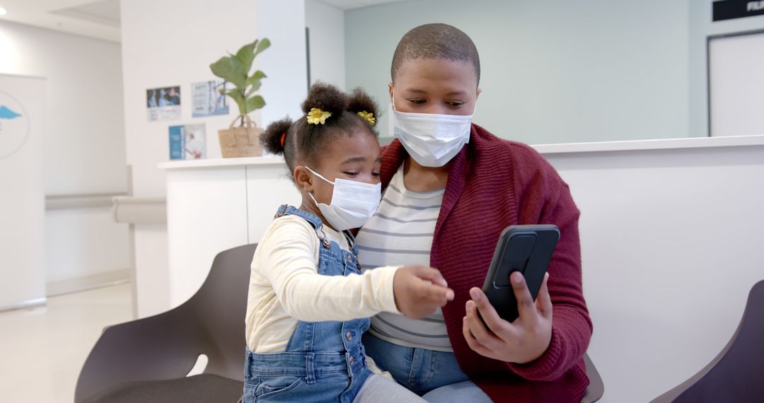 Mother and Daughter in Medical Masks Using smartphone - Free Images, Stock Photos and Pictures on Pikwizard.com