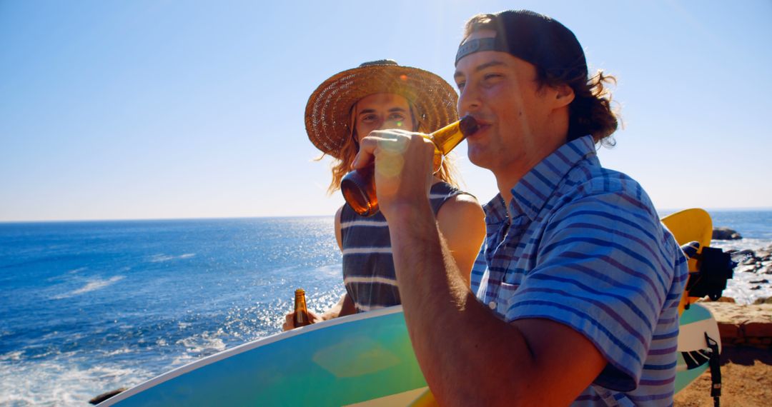 Two Friends Drinking Beer with Surfboards Near Ocean Under Sun - Free Images, Stock Photos and Pictures on Pikwizard.com