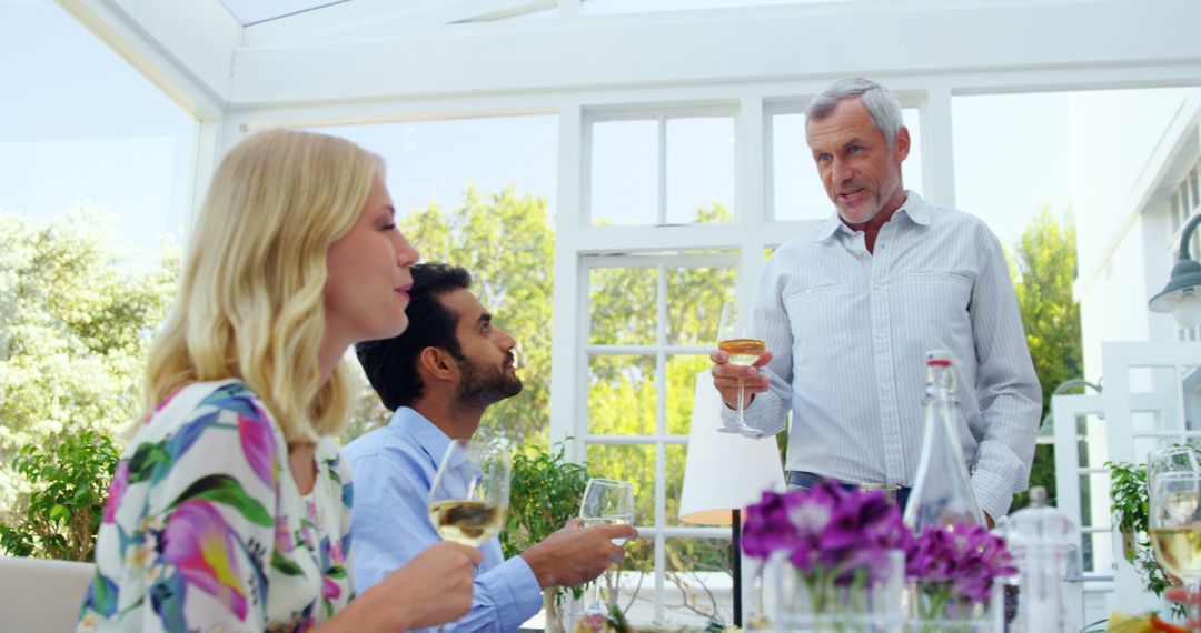 Mature Man Giving Toast During Casual Gathering in Bright Room - Free Images, Stock Photos and Pictures on Pikwizard.com