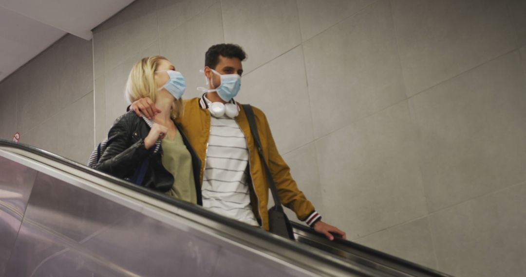 Couple Wearing Protective Masks Riding Escalator Indoors - Free Images, Stock Photos and Pictures on Pikwizard.com