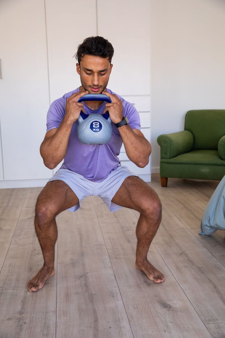 Man Practicing Squats with Kettlebell at Home for Strength Training