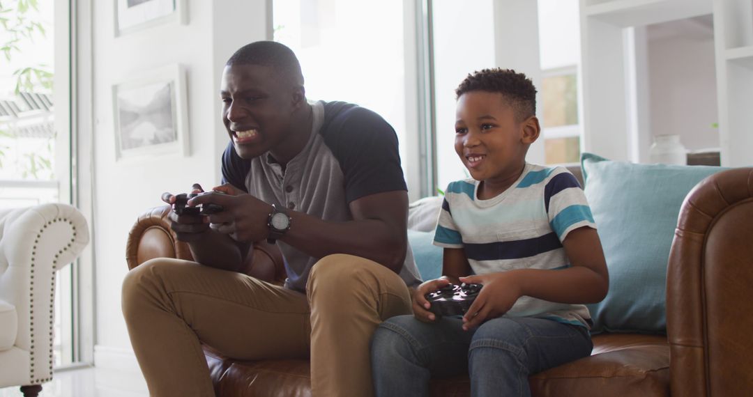 Father and Son Enjoying Video Game on Couch in Modern Living Room - Free Images, Stock Photos and Pictures on Pikwizard.com