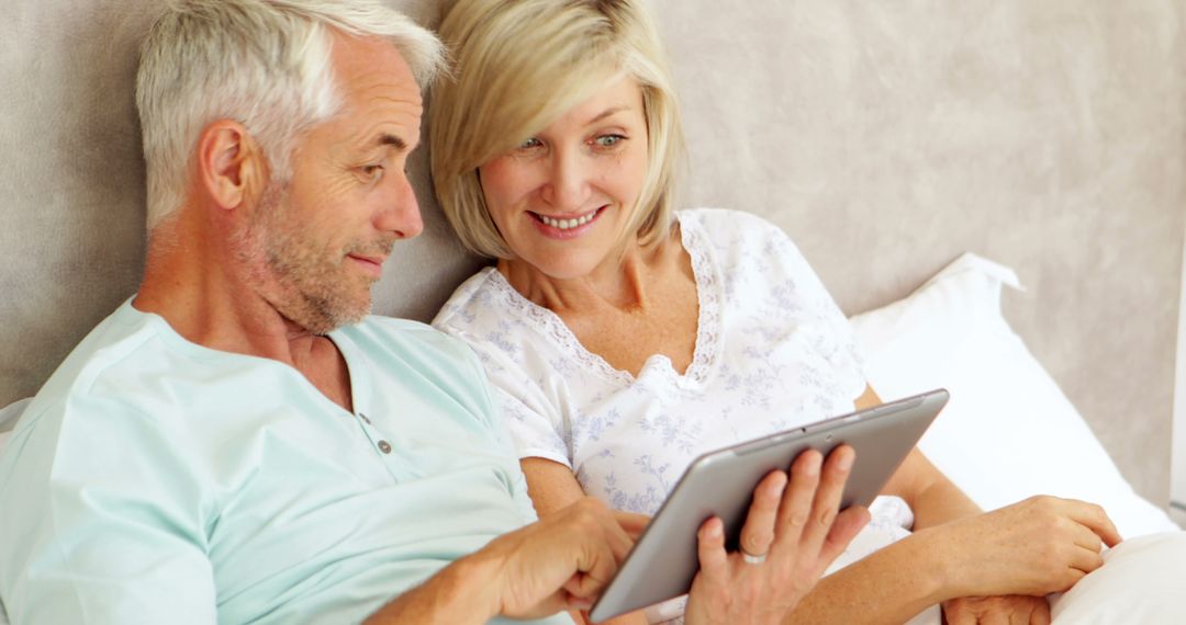 Senior Couple Using Tablet in Bed and Smiling - Free Images, Stock Photos and Pictures on Pikwizard.com