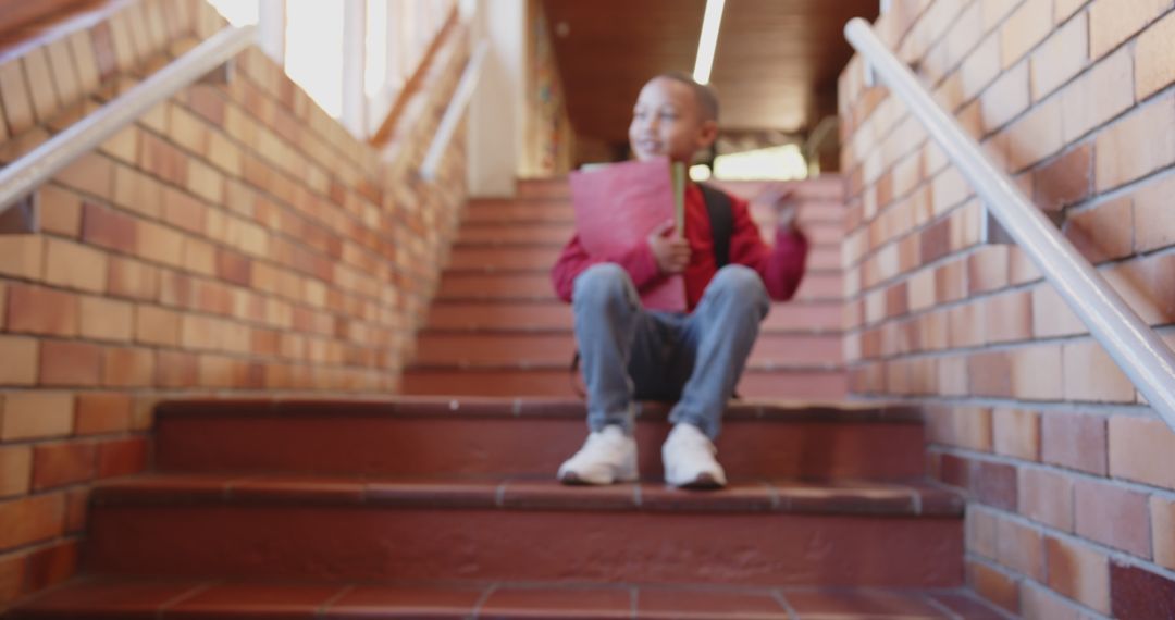 Joyful Schoolboy Relaxing on Stairway with Folder