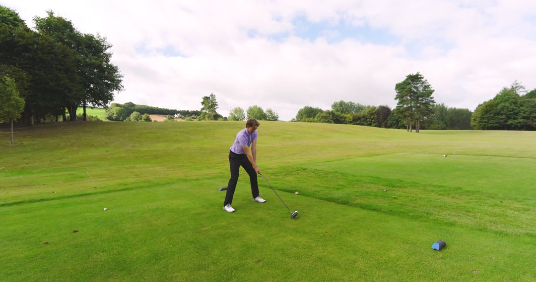 Focused Golfer Swinging Driver Back on Green Course