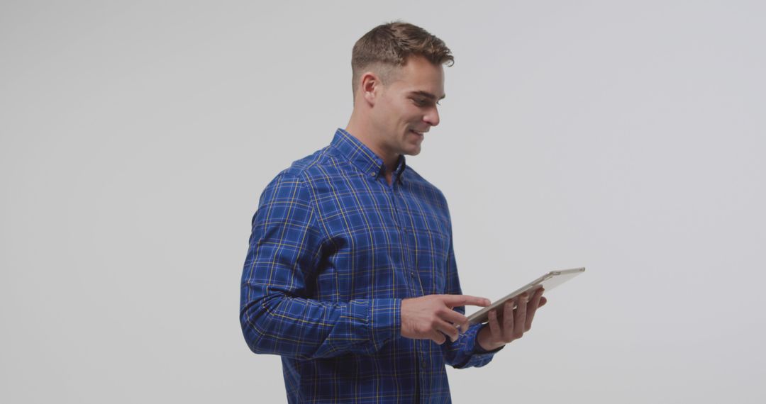 Young man in blue plaid shirt using digital tablet - Free Images, Stock Photos and Pictures on Pikwizard.com