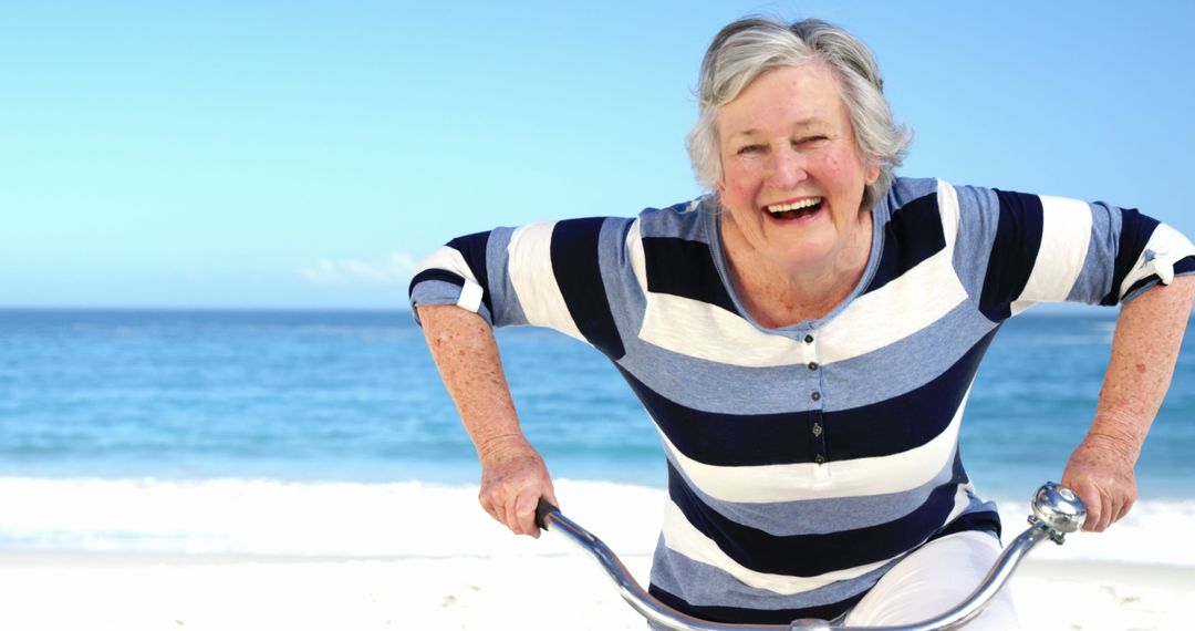 Senior Woman Riding Bicycle at Beach on Sunny Day - Free Images, Stock Photos and Pictures on Pikwizard.com