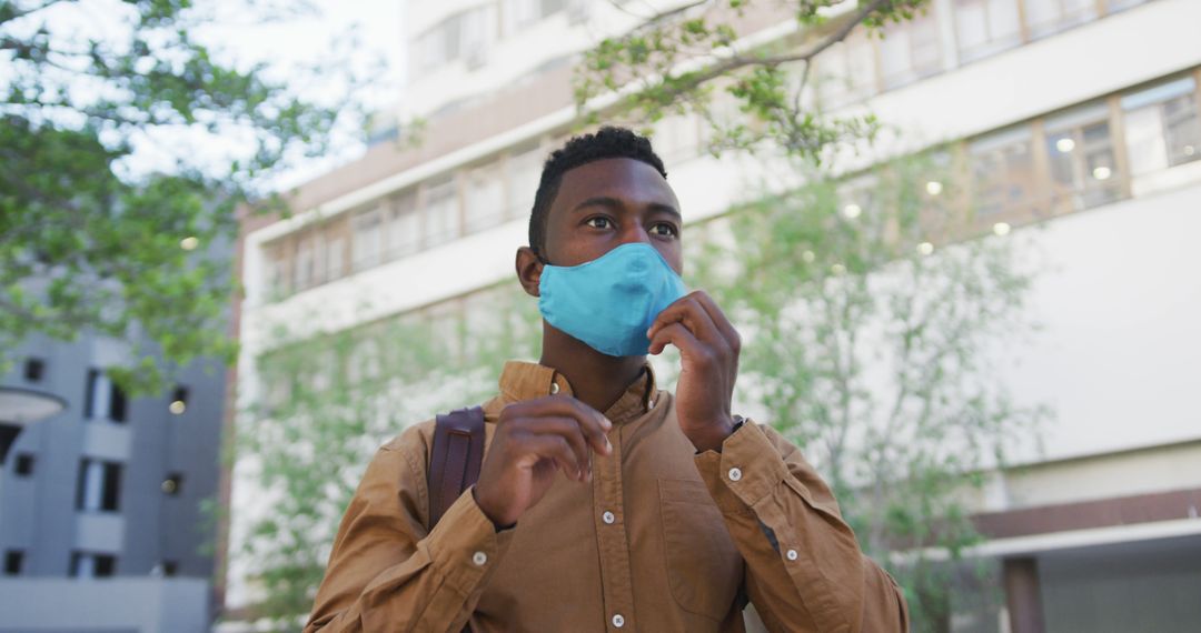 Young Man Putting On Protective Mask Outdoors in Urban Area - Free Images, Stock Photos and Pictures on Pikwizard.com