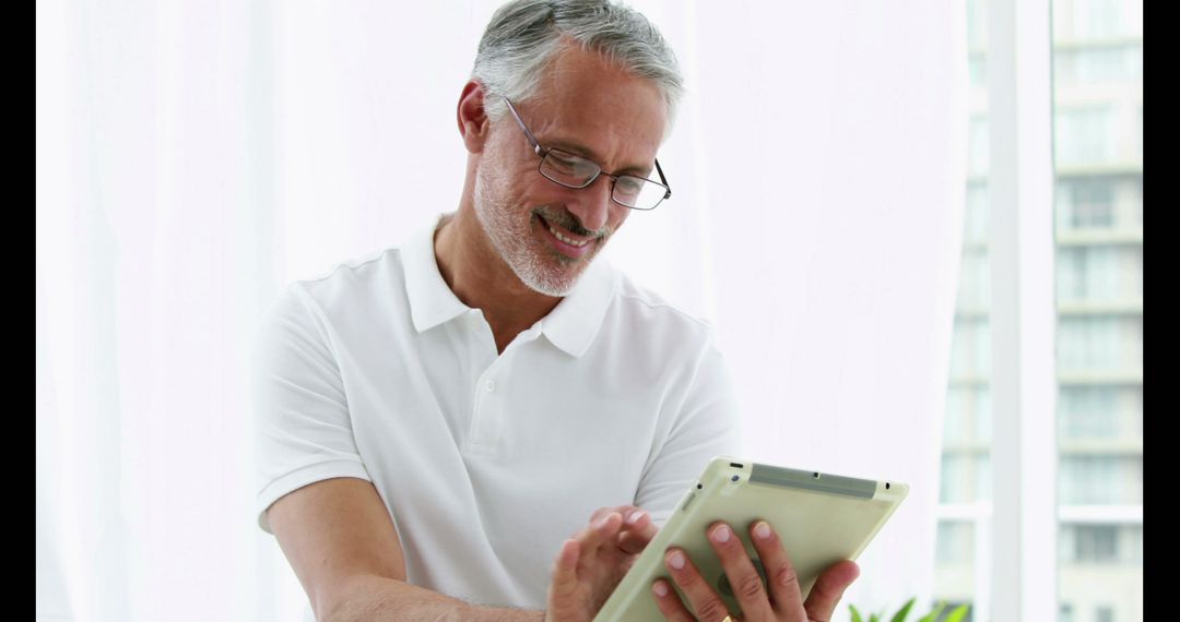 Smiling Mature Man Using Tablet in Bright Office - Free Images, Stock Photos and Pictures on Pikwizard.com