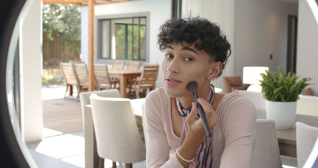 Young Man Applies Blush in Modern Dining Area with Ring Light Mirror