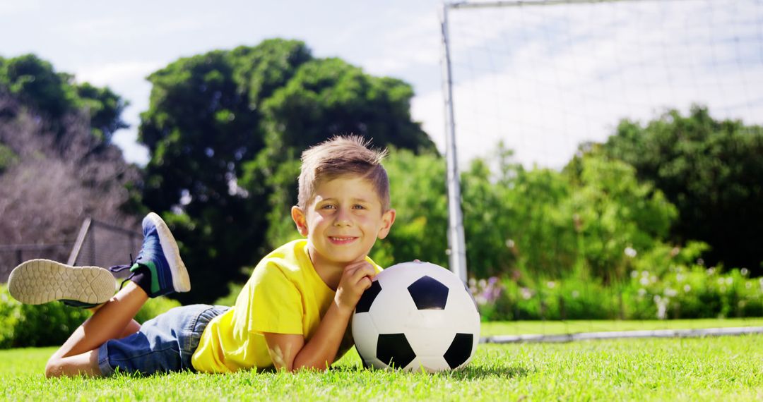 Happy Boy Lying on Grass with Soccer Ball in Park - Free Images, Stock Photos and Pictures on Pikwizard.com