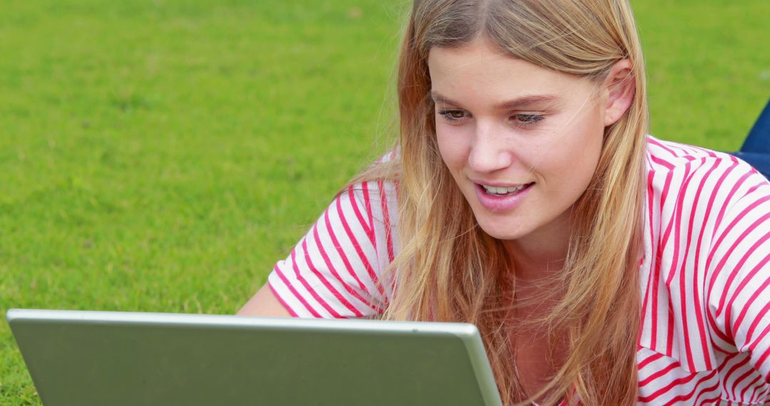 Young Woman Smiling and Using Laptop Outdoors on Green Grass - Free Images, Stock Photos and Pictures on Pikwizard.com