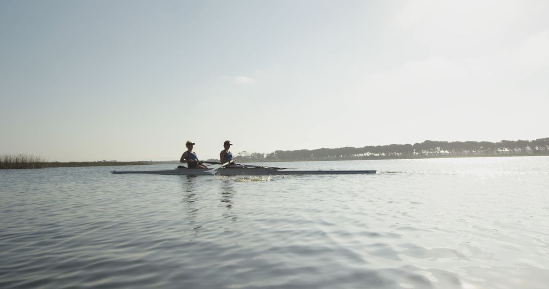 Two Women Rowing on Calm Lake During Daytime in Scenic Nature - Free Images, Stock Photos and Pictures on Pikwizard.com