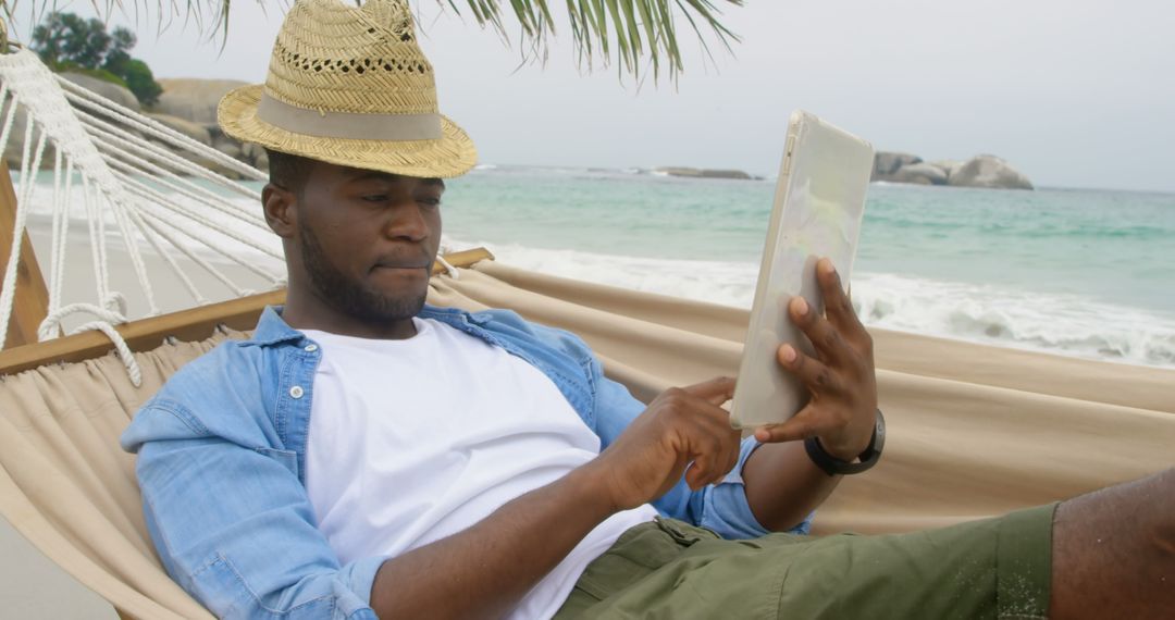 Man Relaxing in Hammock Using Tablet by Beach