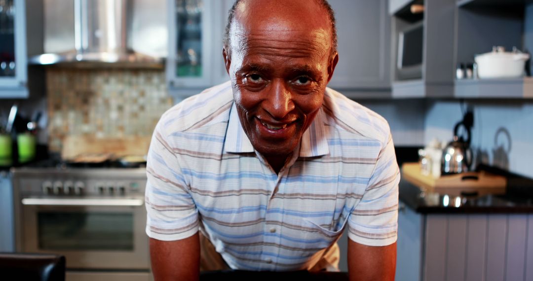 Smiling Senior Man in Kitchen Wearing Striped Polo Shirt - Free Images, Stock Photos and Pictures on Pikwizard.com