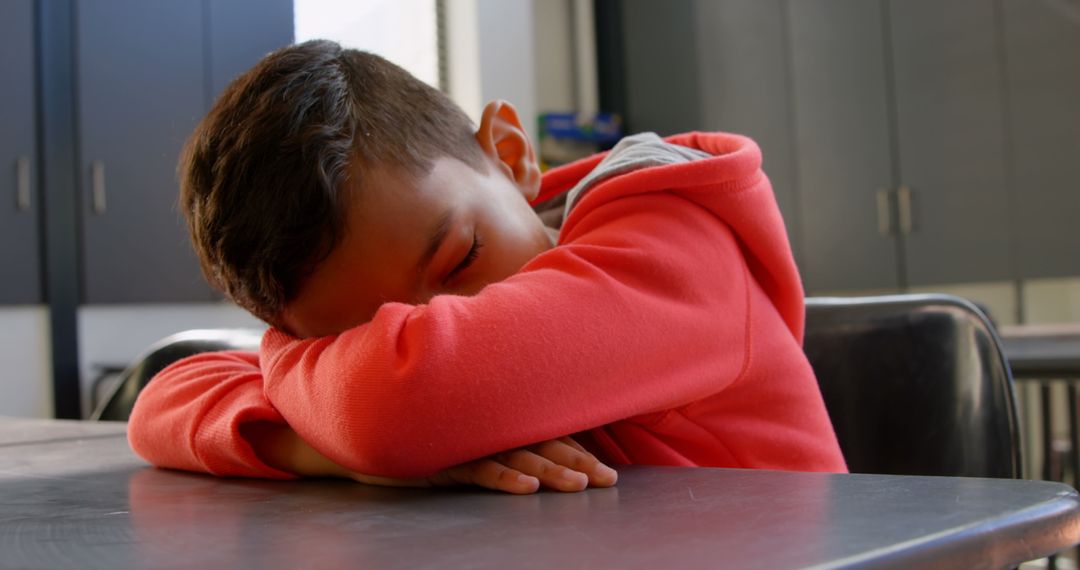 Tired Schoolboy Sleeping on Desk in Classroom